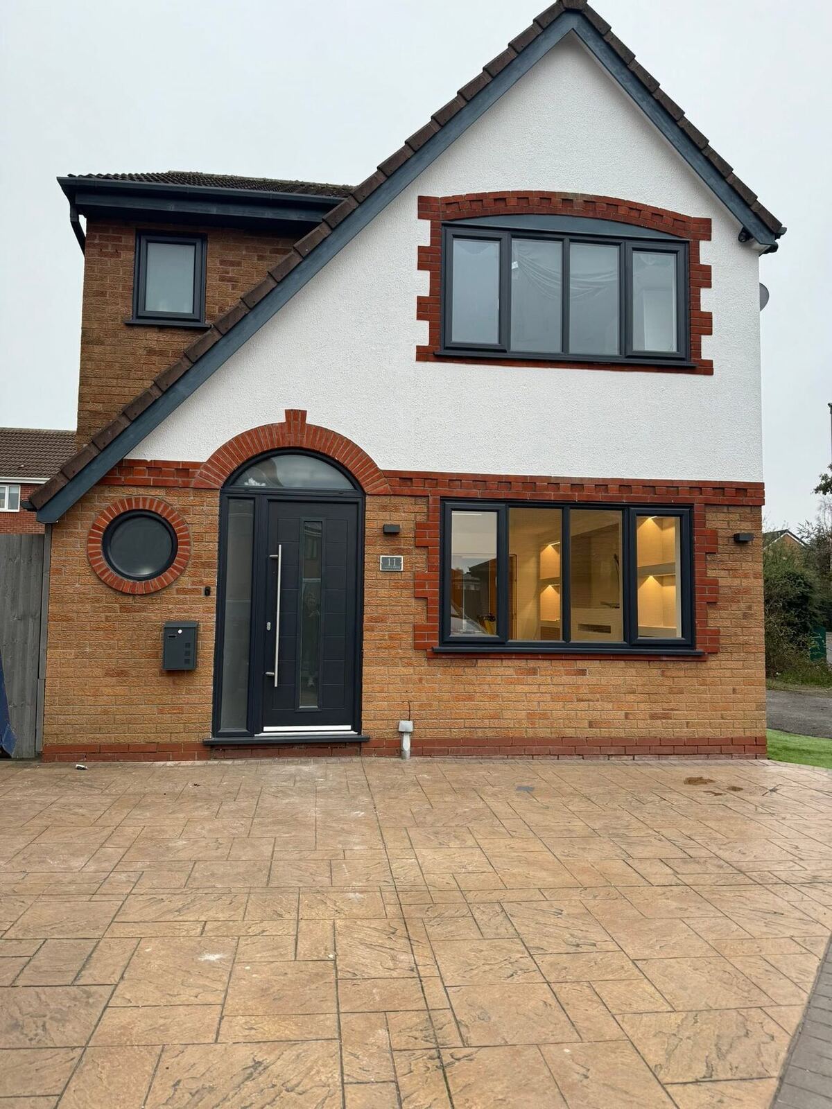 Dark composite front door on a rendered house