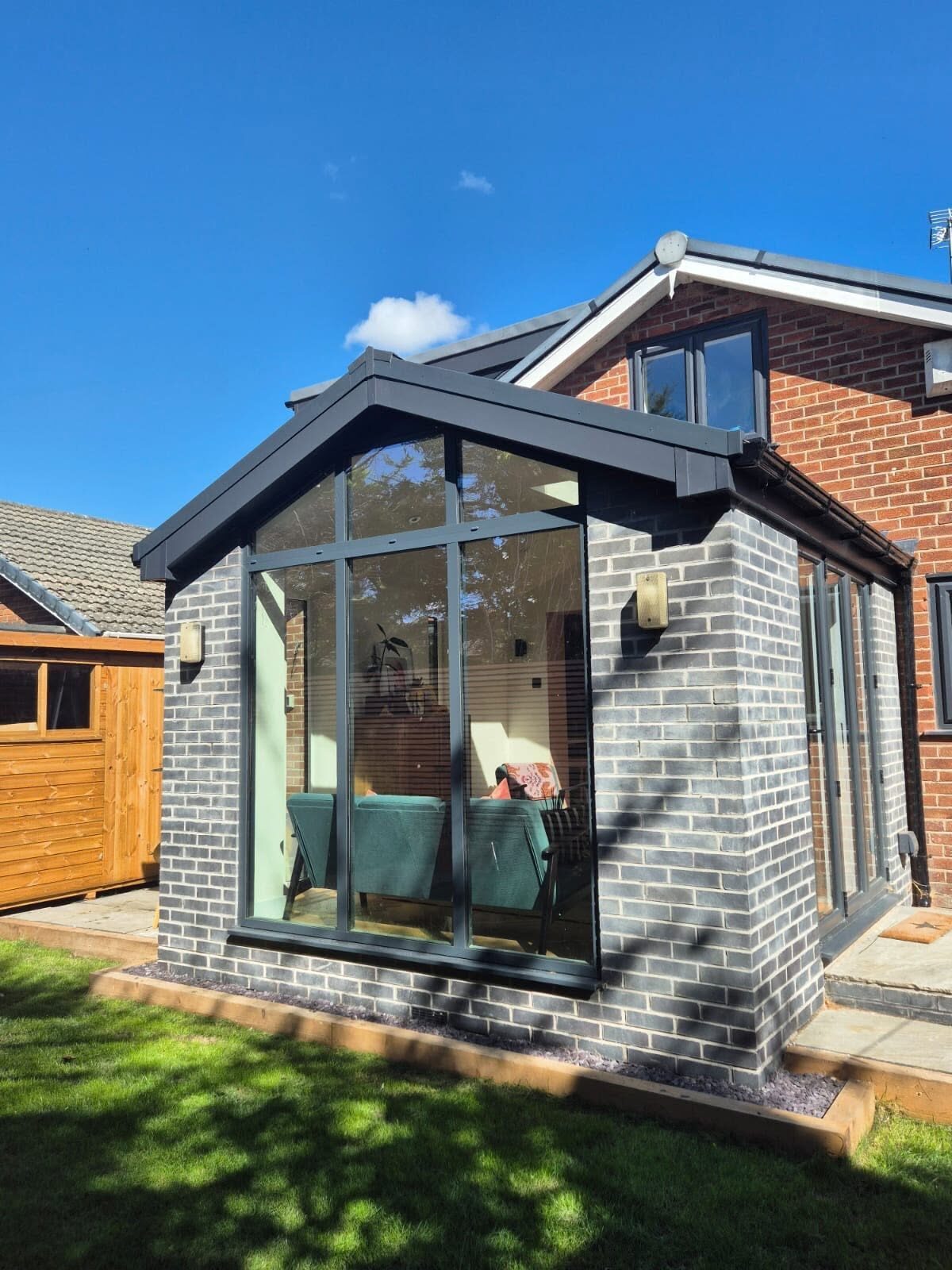 Grey brick extension with a solid roof and anthracite windows