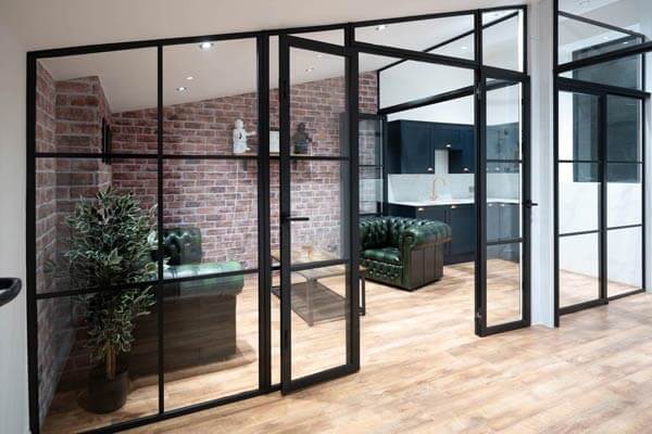 Glazed internal screen against exposed brickwork, kitchen beyond