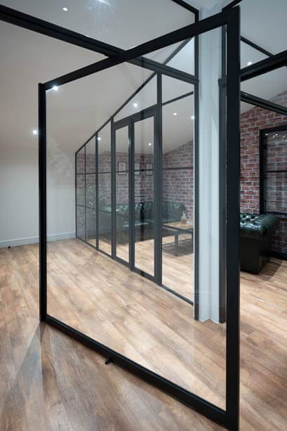 Full height black framed glazed partition running along a living room wall