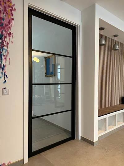 Single black framed glazed door opening onto a hallway