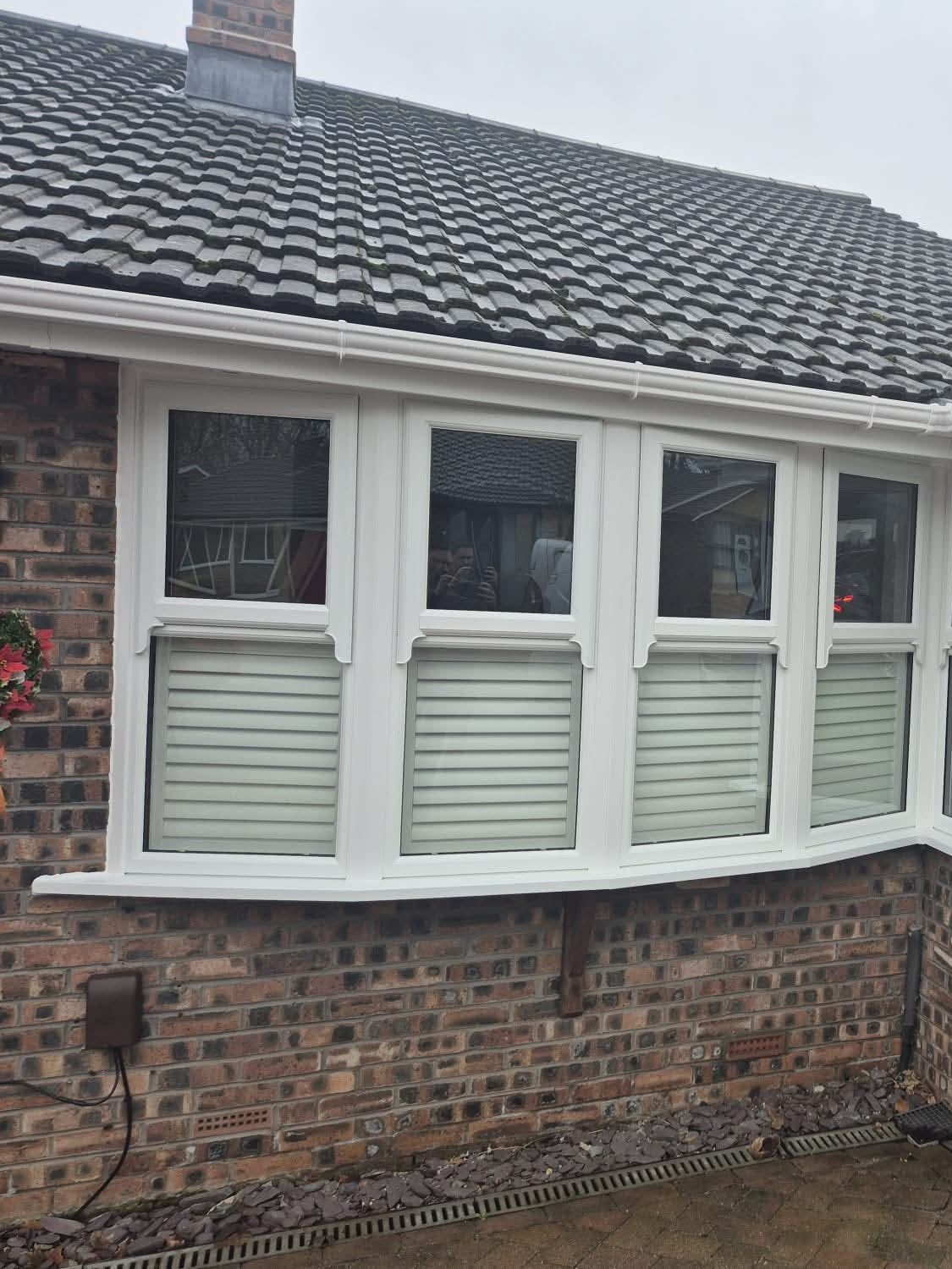 White uPVC bay window with shutters on a brick bungalow